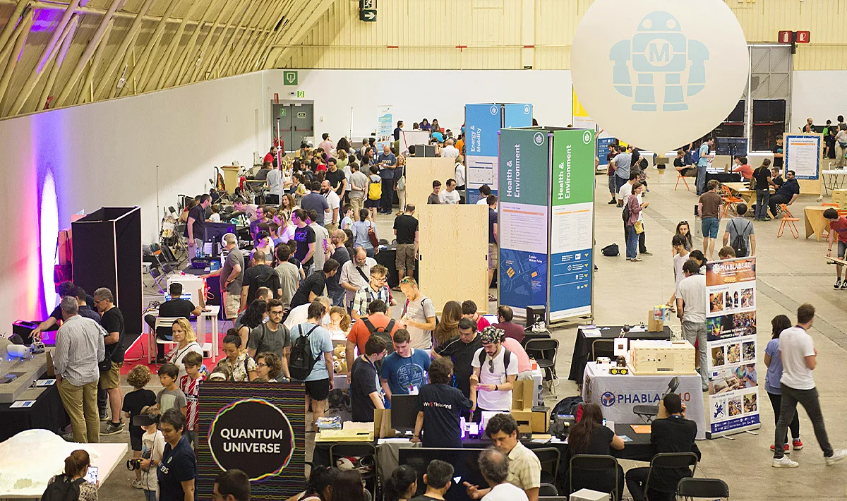 Aerial image of Maker Faire Barcelona edition 2018 showing the expositors tables and the visitors interacting with them.